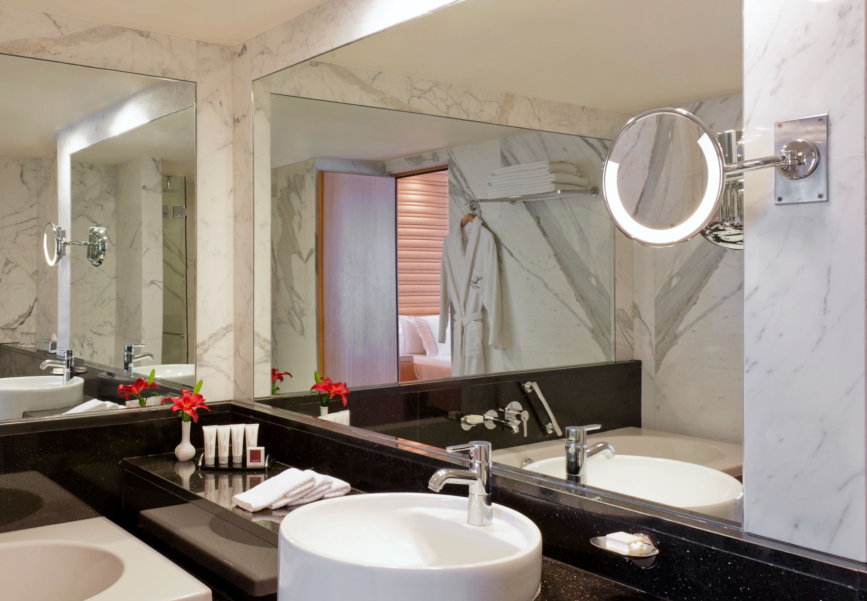 A modern bathroom with two sinks, a large mirror, and a towel rack.