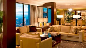 A modern hotel lobby with a large seating area, large windows offering a city view, and decorative lighting.