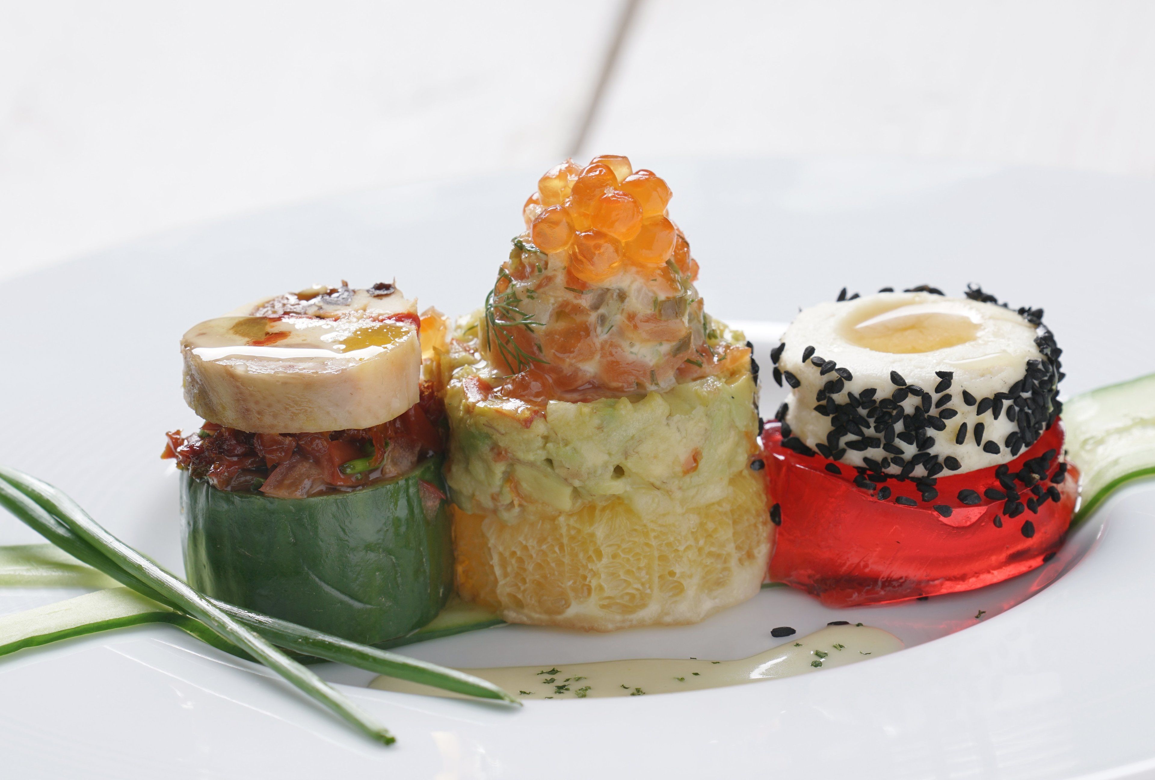 Three distinct food items on a white plate, each with unique toppings and garnishes.