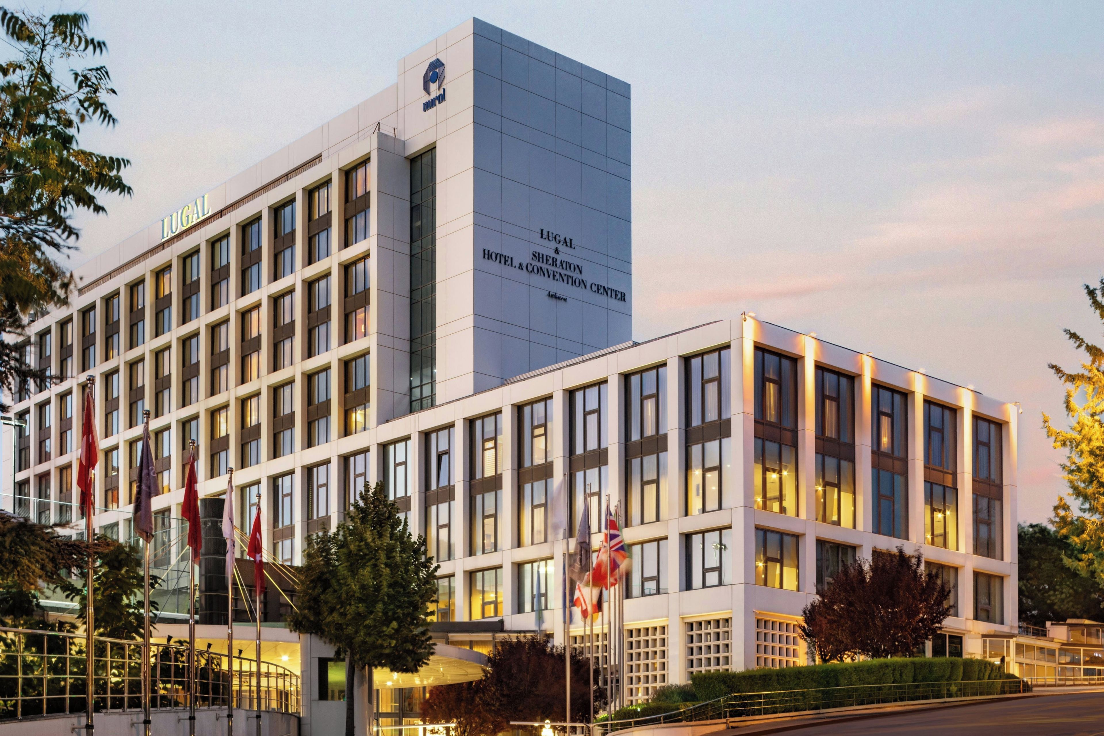 A modern hotel building with multiple floors, large windows, and a prominent signage for the hotel and convention center.