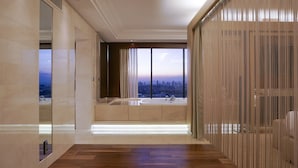 A modern bathroom with a large window, a bathtub, and a vanity.