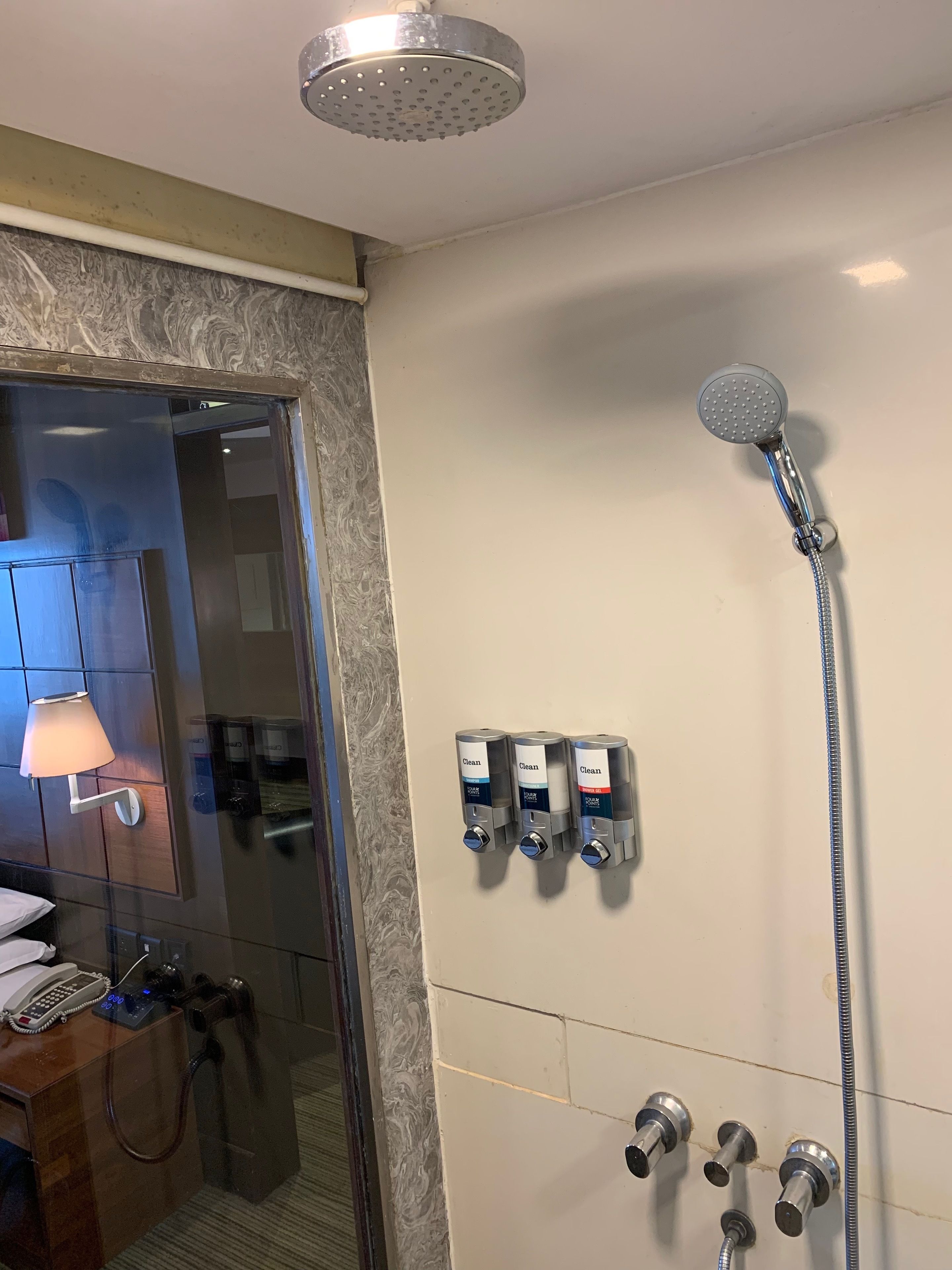 A bathroom with a shower, a mirror, a towel rack, and a phone.