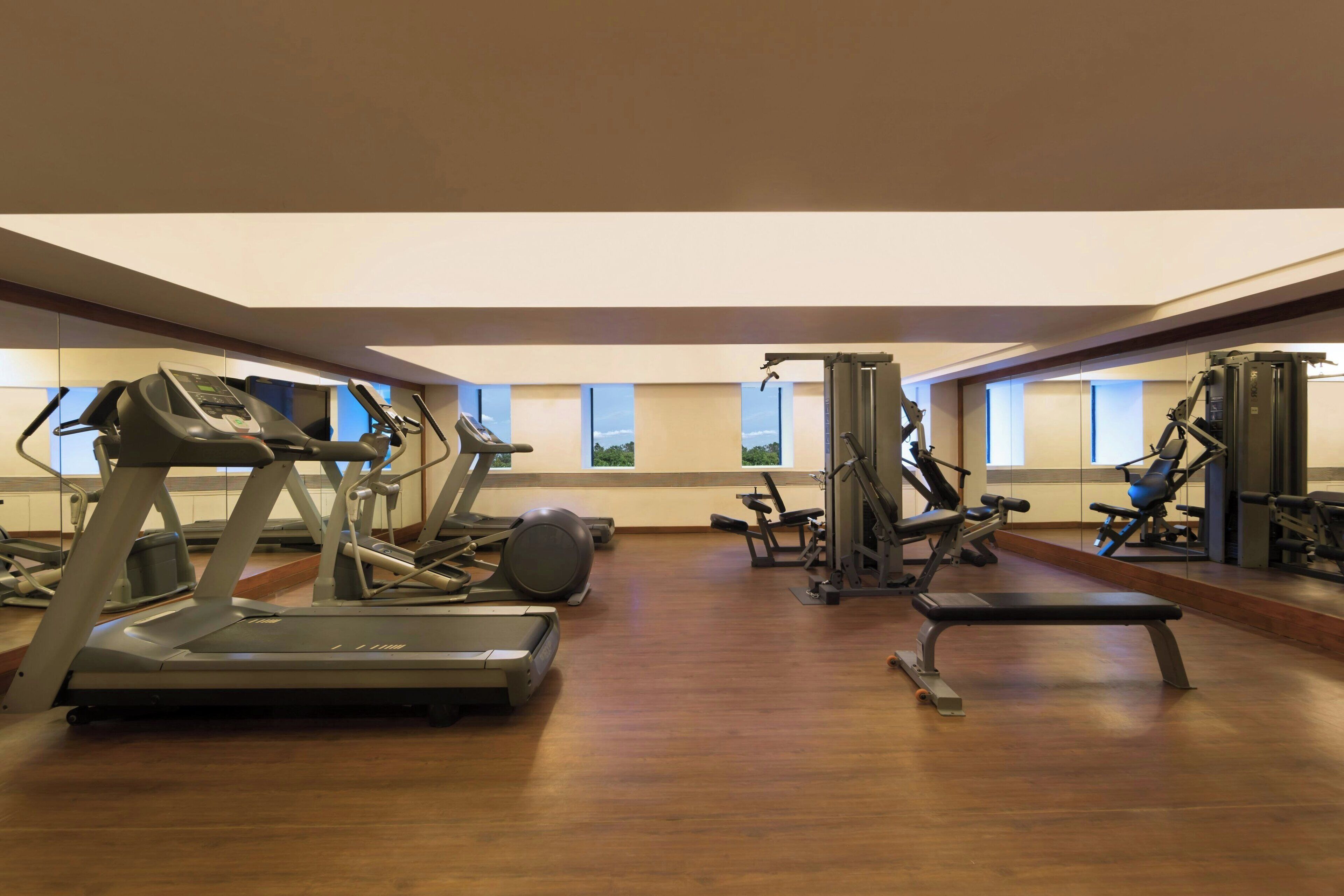 Un gimnasio amplio con cintas de correr, elípticas y equipos de levantamiento de pesas.