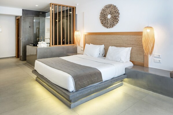 Habitación de hotel moderna con una cama grande, una mesita de noche, un espejo y un adorno en la pared.