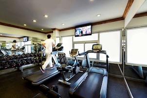 Un gimnasio con cintas de correr, mancuernas y una pantalla de televisión.