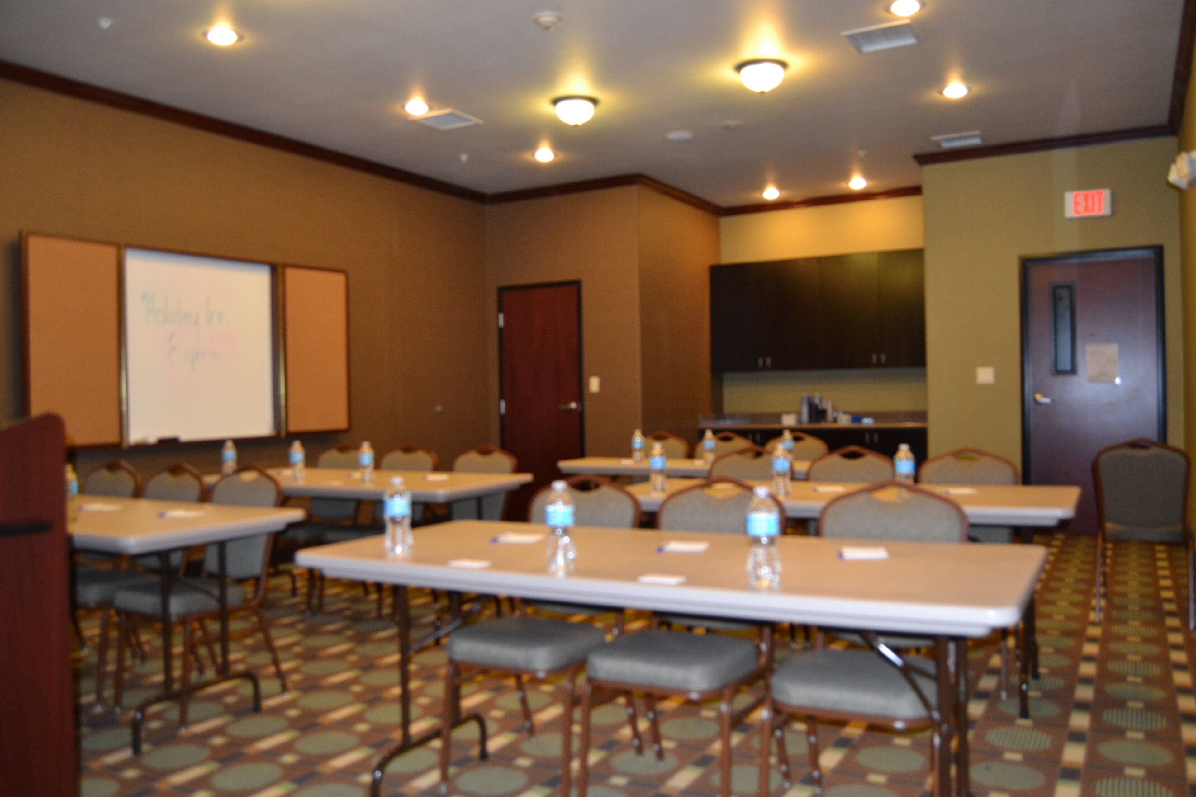 A conference room with tables, chairs, and a whiteboard.