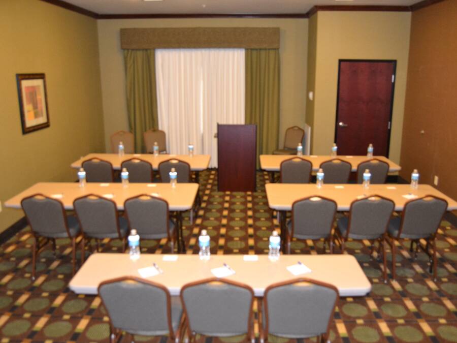 A conference room with multiple tables and chairs, arranged in a U-shape.