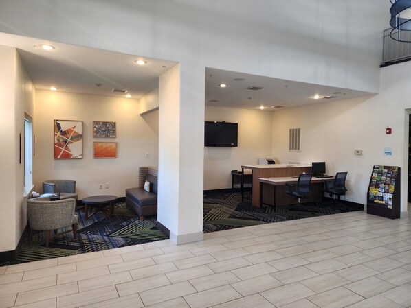 Een hotel lobby met een receptiebalie, een zithoek en een business center.
