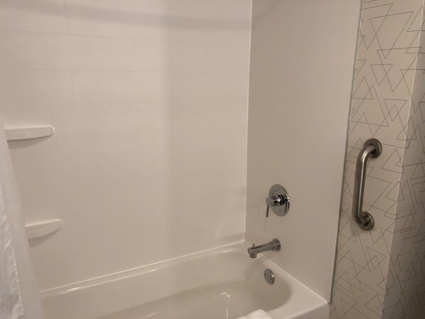 A bathtub with a handheld showerhead and a grab bar on the wall.