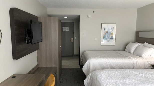 A hotel room with two beds, a desk, a chair, a TV mounted on the wall, and a door leading to another room. - Holiday Inn Express Hotel & Suites Donegal by IHG (Stahlstown)