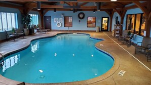 An indoor swimming pool with a wooden ceiling and walls, surrounded by lounge chairs and a small seating area. - Holiday Inn Express Hotel & Suites Donegal by IHG (Stahlstown)