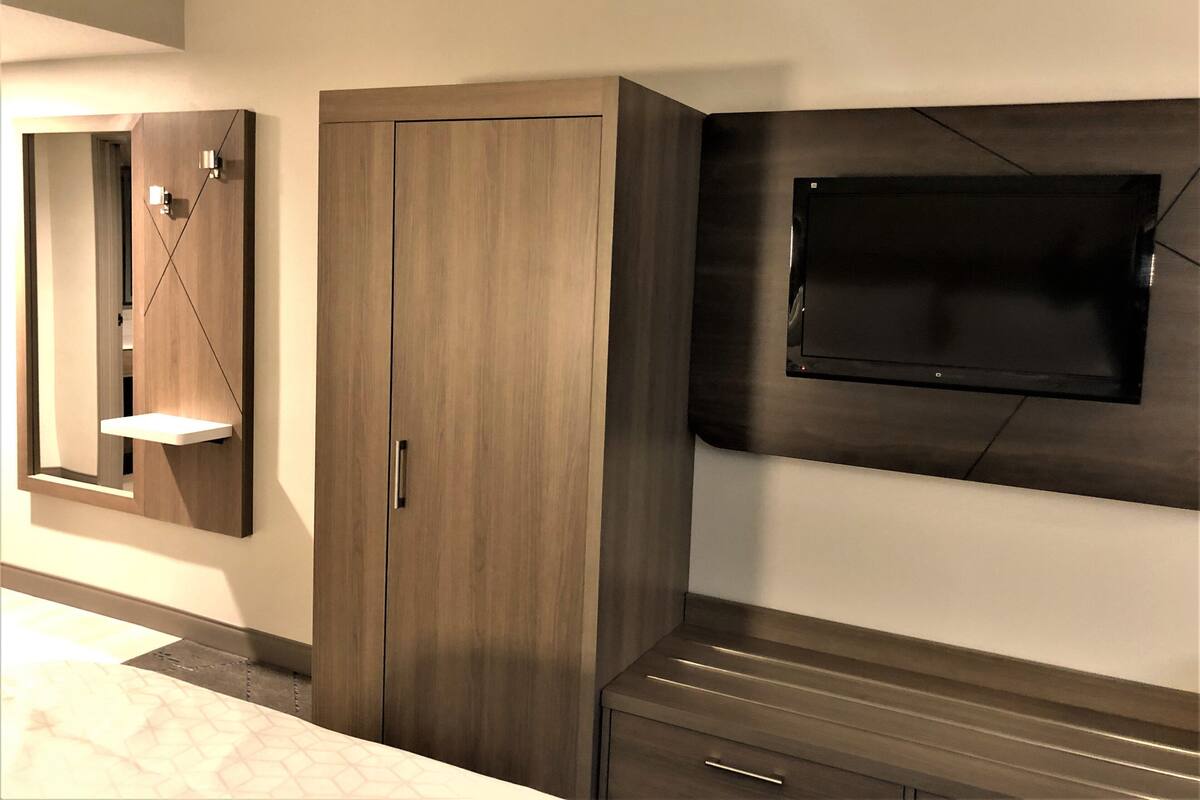 A modern room with a wardrobe, a mirror, and a flat-screen TV mounted on the wall.