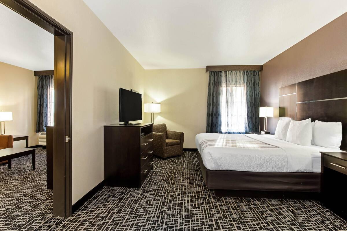 Ein Hotelzimmer mit Bett, Fernseher, Schreibtisch, Stuhl und Lampe.
