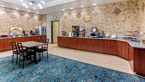 A hotel lobby with a reception desk, a clock, a sun decoration, and a blue patterned carpet. - La Quinta Inn & Suites by Wyndham Denver Gateway Park (Denver)