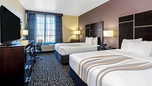 A hotel room with two beds, a desk with a TV, a chair, and a window with curtains. - La Quinta Inn & Suites by Wyndham Denver Gateway Park (Denver)