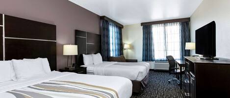 A hotel room with two beds, a desk, a television, and a chair.