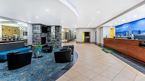 A hotel lobby with a reception desk, seating area, and a cityscape mural. - La Quinta Inn & Suites by Wyndham Denver Gateway Park (Denver)