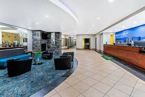A hotel lobby with a reception desk, seating area, and a cityscape mural. - La Quinta Inn & Suites by Wyndham Denver Gateway Park (Denver)