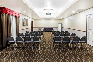 A conference room with a patterned carpet, rows of chairs, a projector, and a whiteboard. - La Quinta Inn & Suites by Wyndham Denver Gateway Park (Denver)