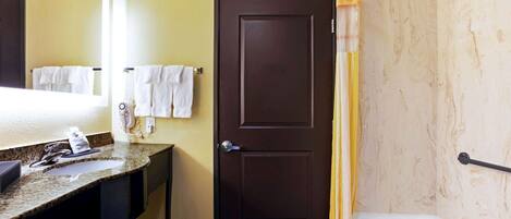 Un baño con lavamanos, espejo, toallero, puerta y bañera.