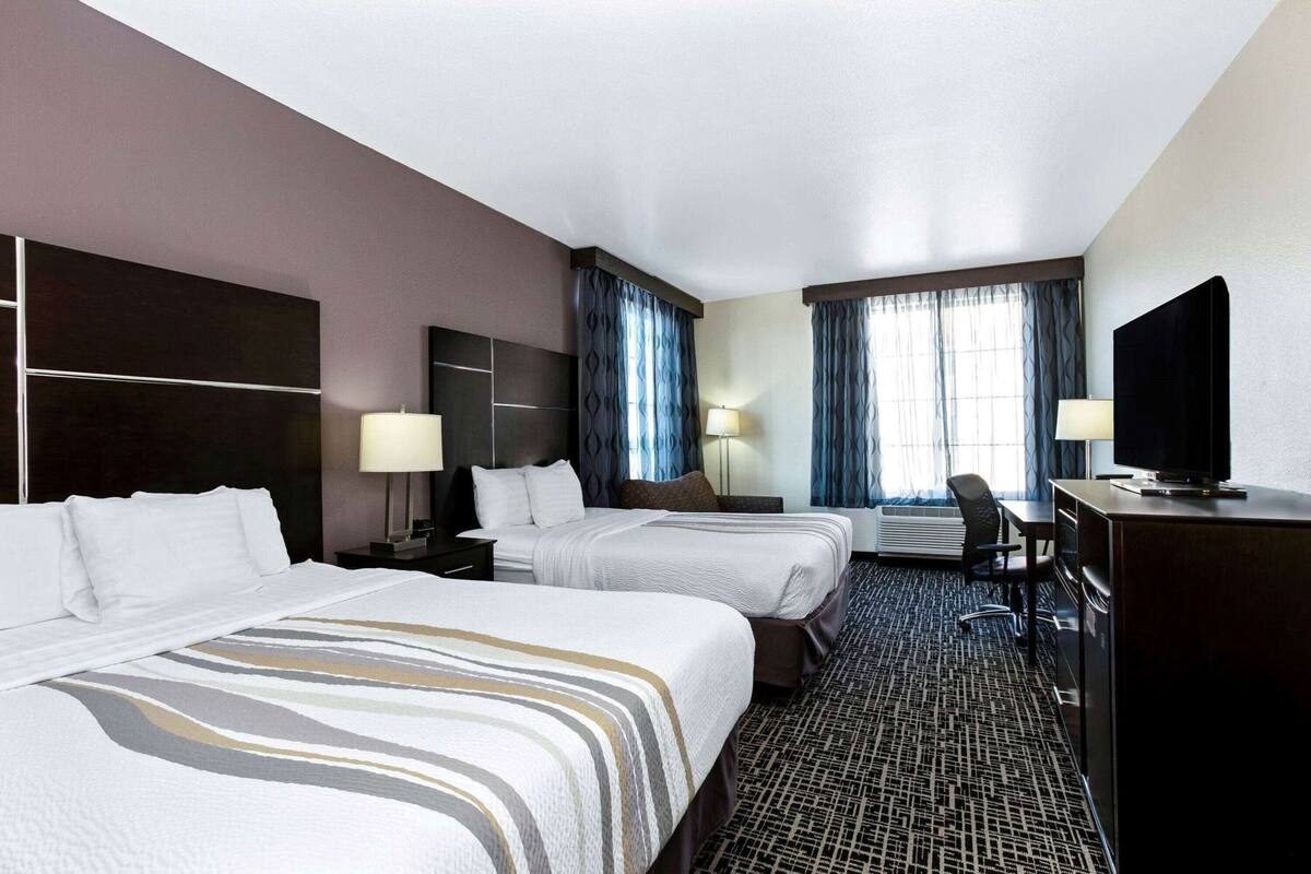 Ein Hotelzimmer mit zwei Betten, einem Schreibtisch, einem Fernseher und einem Sessel.