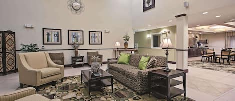 A spacious living area with a sofa, armchairs, a coffee table, and a patterned rug.