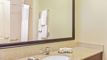 Un baño con lavamanos, espejo y perchero para toallas.