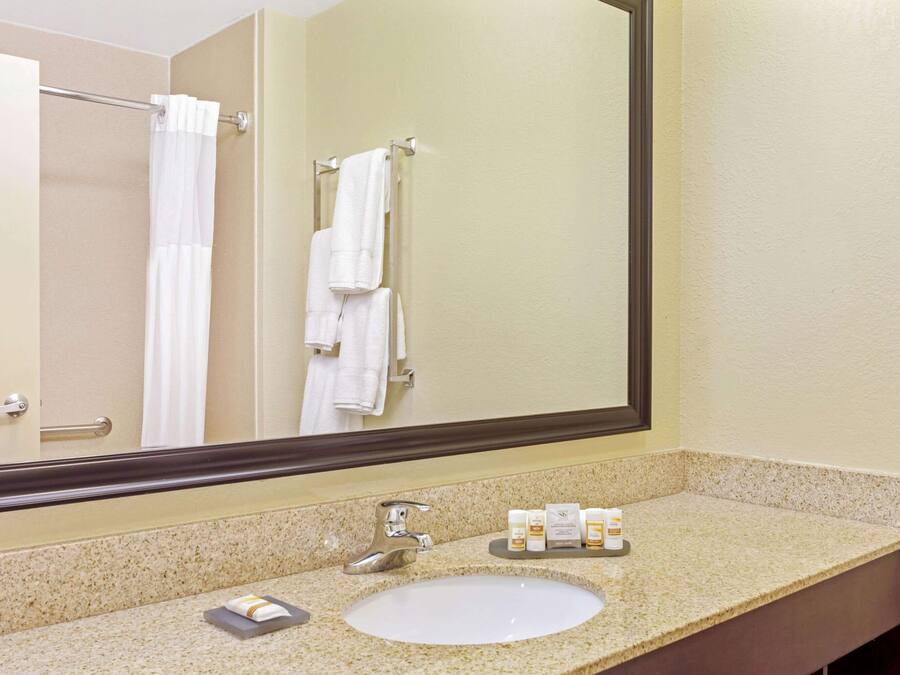 A bathroom with a sink, mirror, and towel rack.