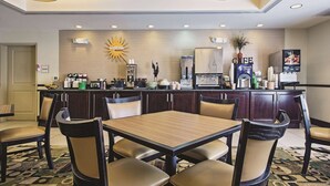 Un hall de hotel con mostrador de recepción, estación de café y una zona de estar con mesa y sillas.