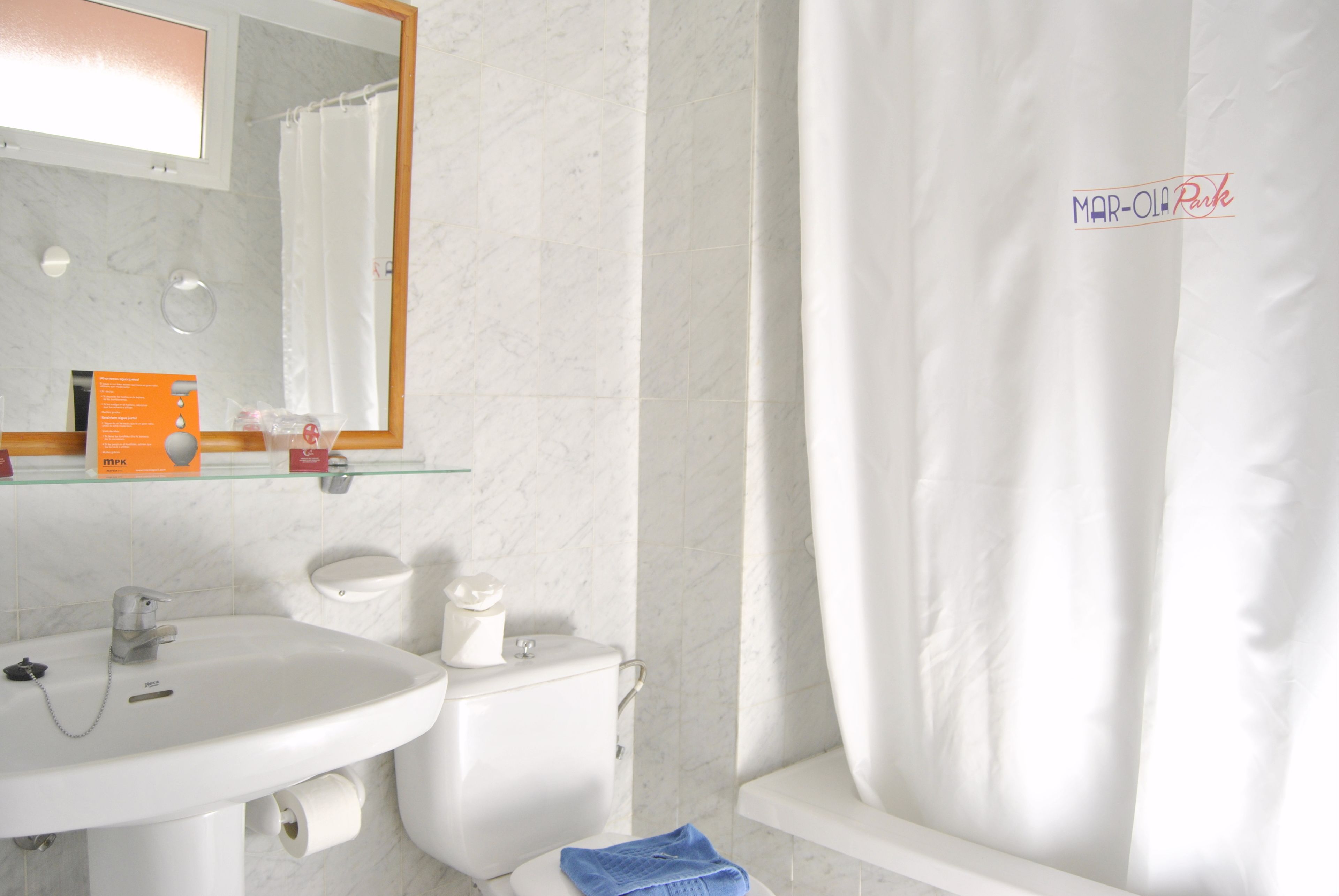 A bathroom with a white sink, toilet, and shower curtain.