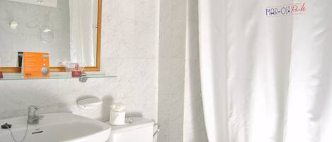 A bathroom with a white sink, toilet, and shower curtain.