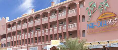 Un hôtel rose doté de balcons et d’une enseigne à thème tropical.