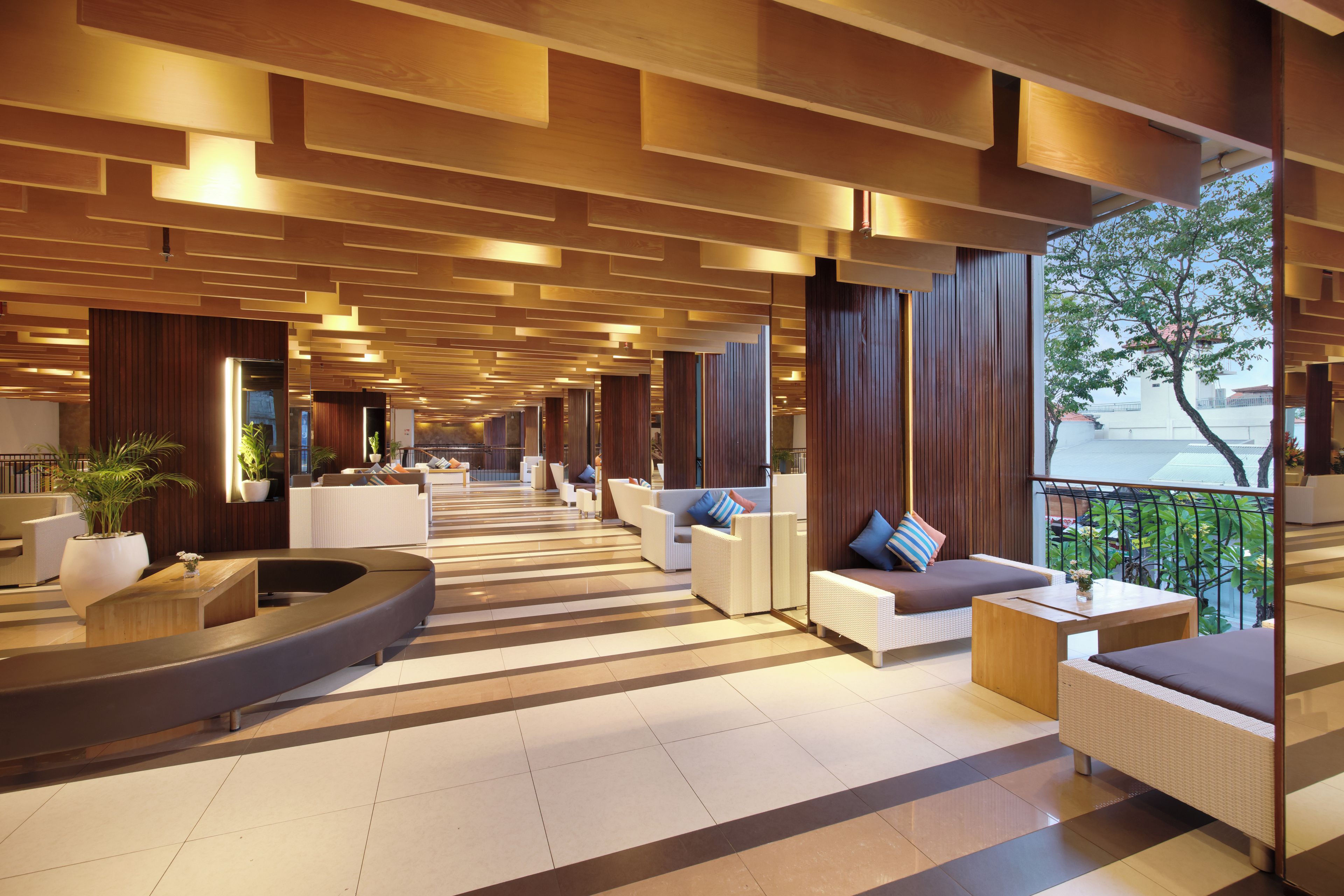 A modern hotel lobby with a long corridor, seating areas, and large windows.