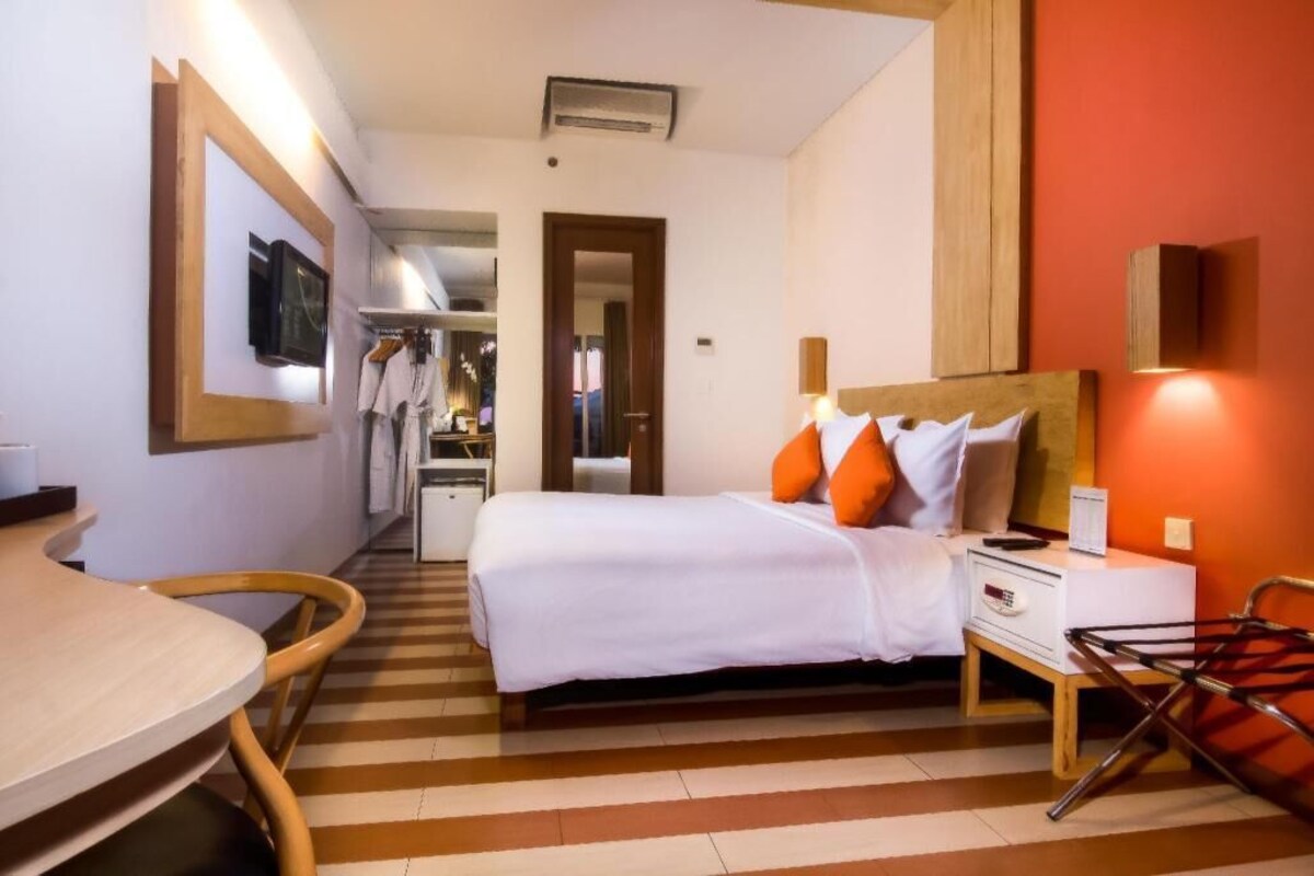 A hotel room with a bed, bedside table, chair, and a small table with a chair.