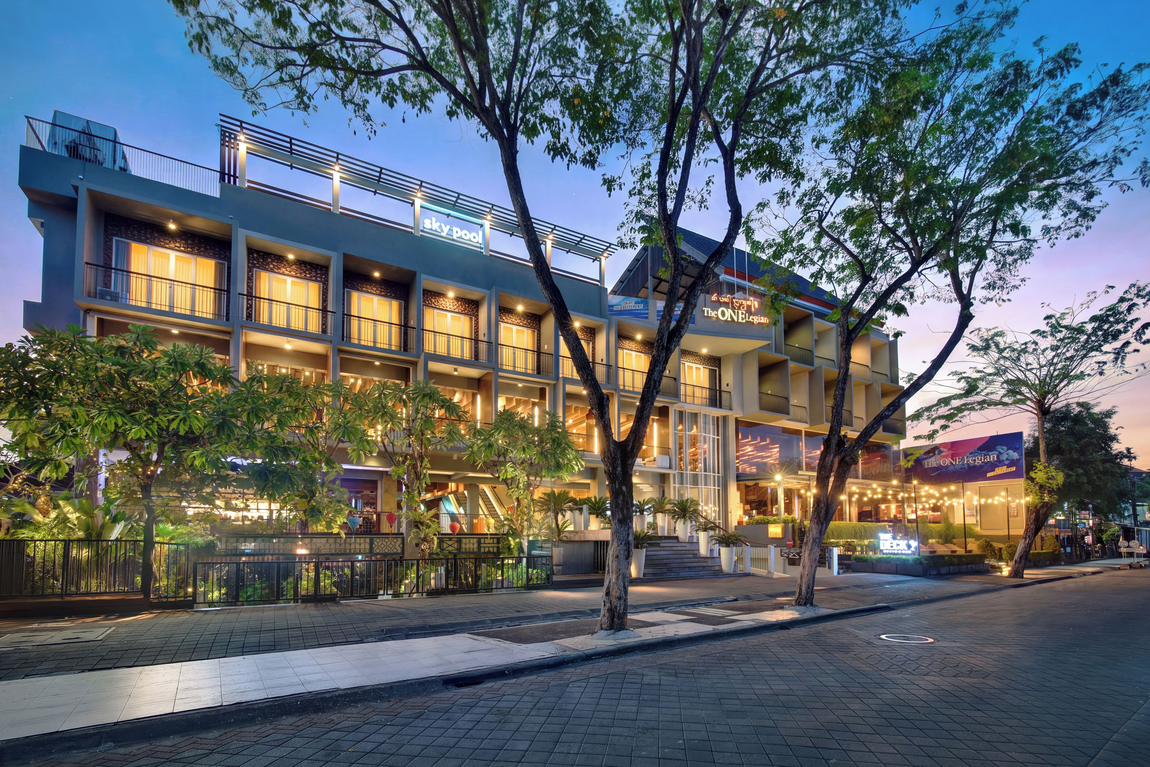 A multi-story hotel with a balcony, outdoor seating, and a sign for 'The ONE Legion.'