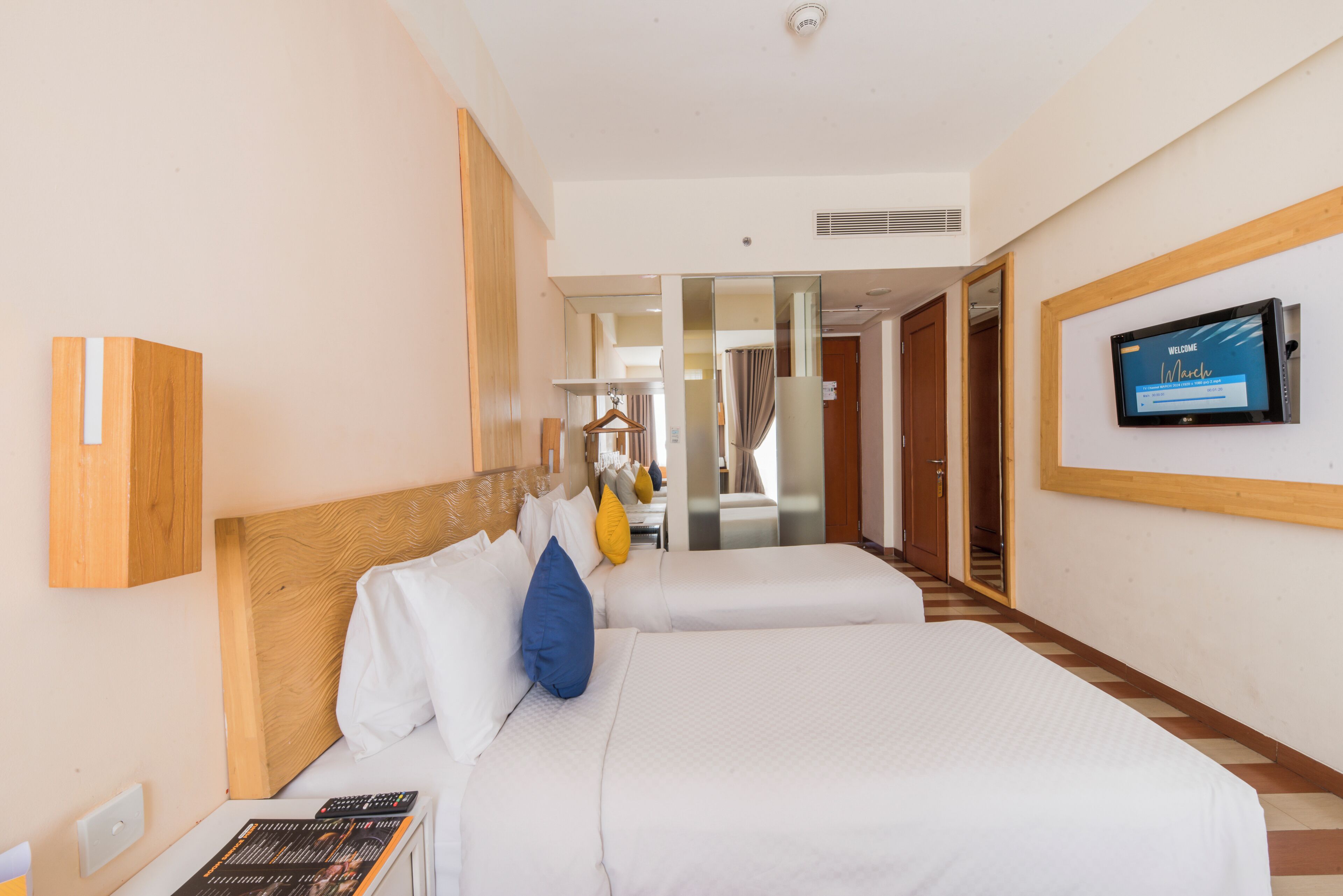 Een hotelkamer met twee bedden, een televisie en een spiegel.