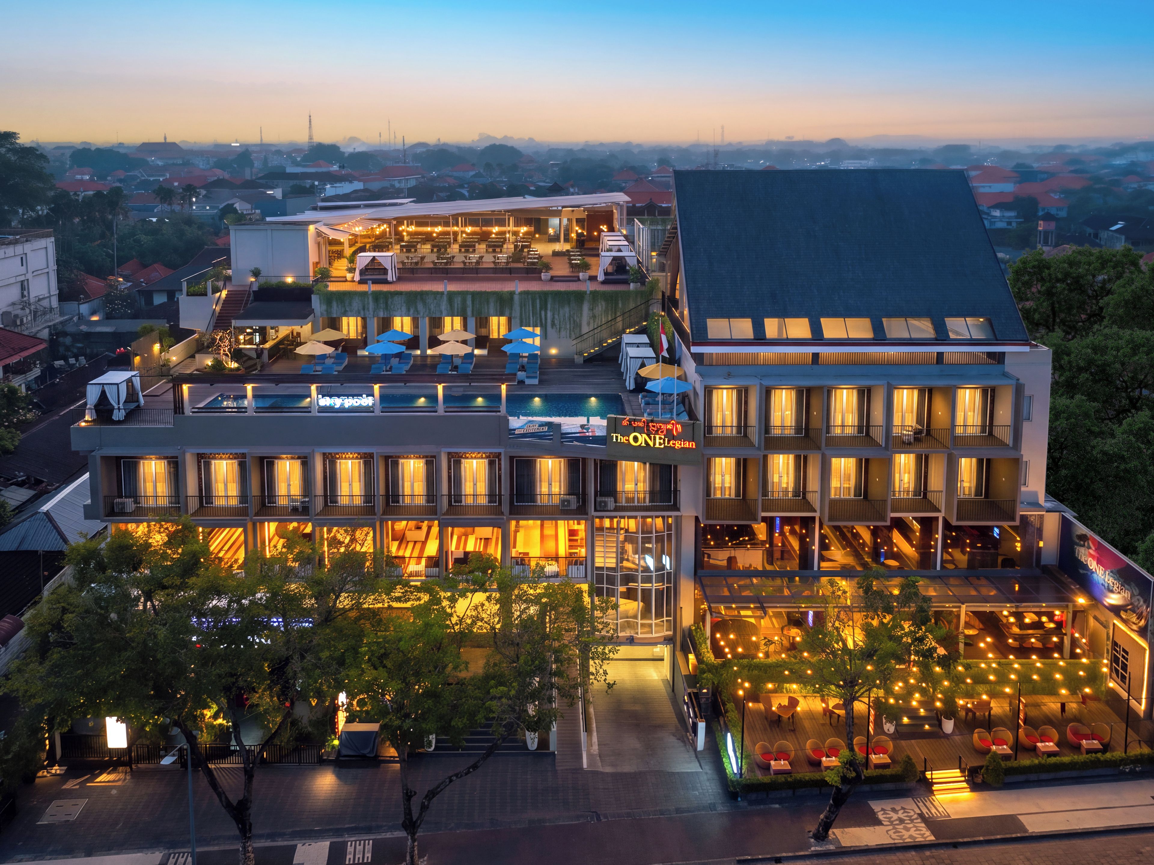 A multi-story hotel with outdoor seating and a pool area.