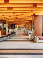 Um hall amplo com teto de madeira moderna, uma escadaria central e áreas de estar.