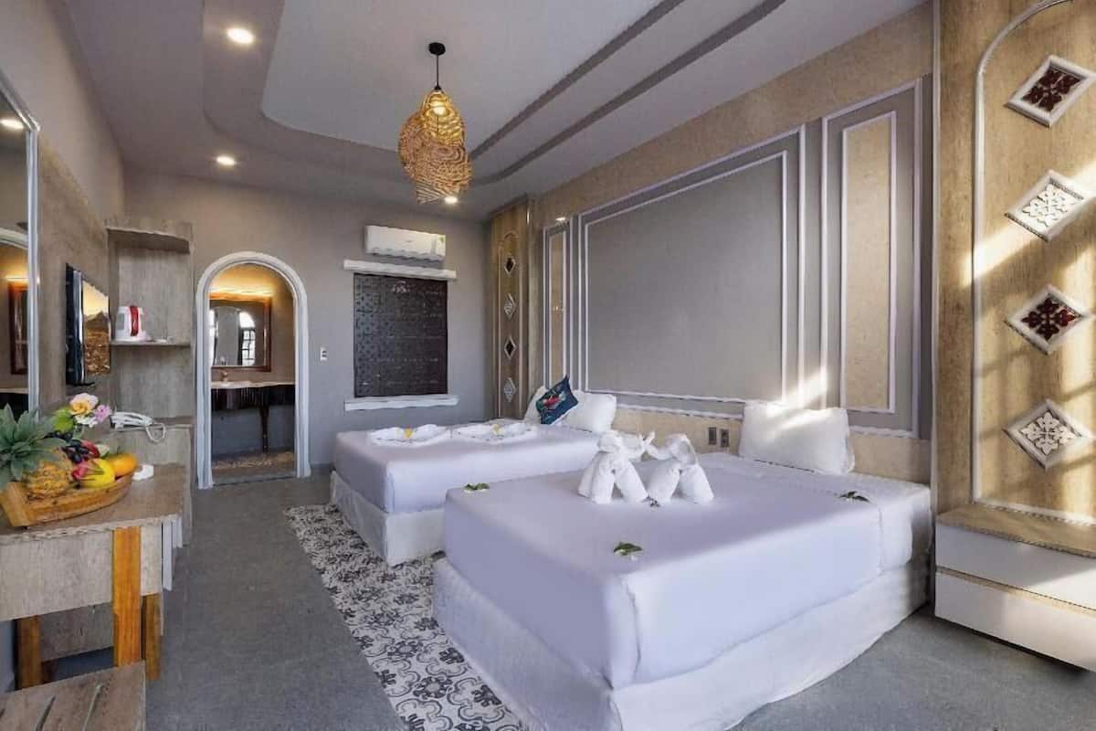 A hotel room with two beds, a dining area, and a bathroom.