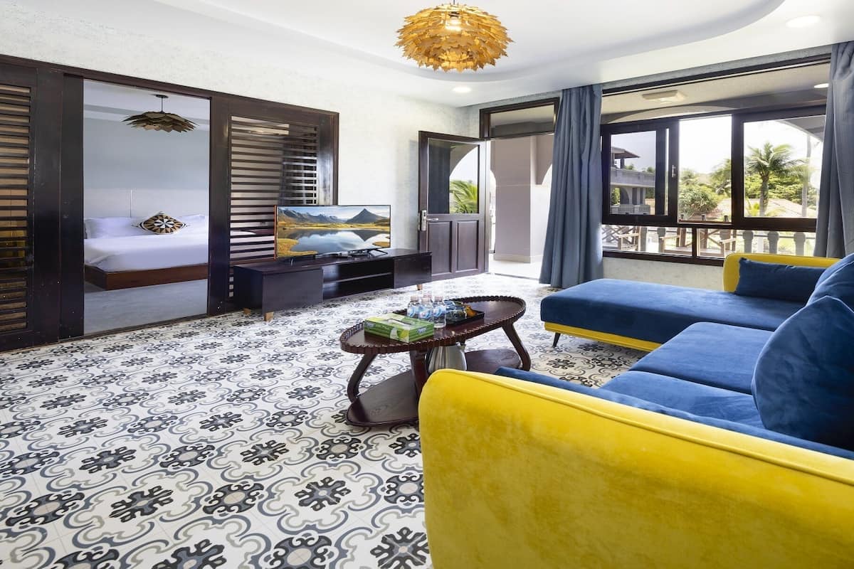 A modern hotel room with a bed, a sofa, a TV, and a balcony with a view.