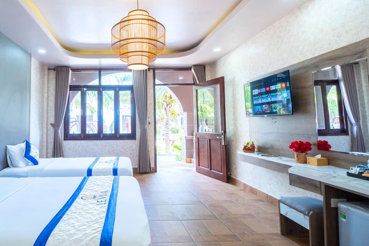 A hotel room with two beds, a TV, a desk, and a bathroom.