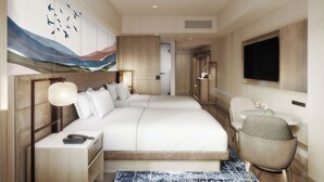 Una habitación de hotel moderna con una cama grande, mesitas de noche, un escritorio, una silla, un televisor de pantalla plana y obras de arte en la pared.