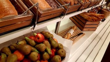 Un bufé con diversas opciones de comida, como pan, pasteles y frutas.