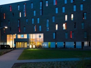 Un bâtiment moderne à la façade plate, doté de nombreuses fenêtres et d’une entrée bien éclairée.