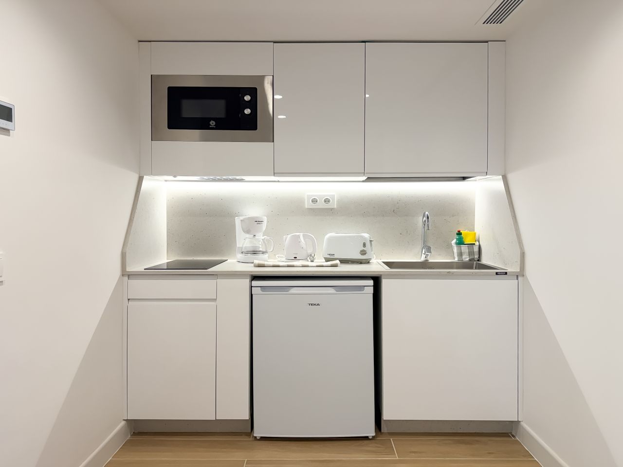 Una kitchenette compacta equipada con microondas, cafetera, tostadora y lavavajillas.