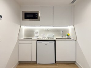 A compact kitchenette with a microwave, coffee maker, toaster, and dishwasher.