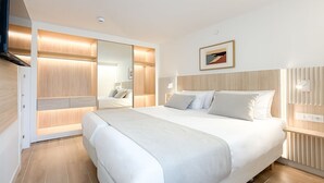 A modern bedroom with a large bed, built-in wardrobe, and a bedside table. - Aparthotel Playa del Sol - Adults Only (San Bartolomé de Tirajana)