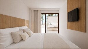 Quarto de hotel moderno com uma cama grande, TV de tela plana na parede e vista para o exterior por uma porta de vidro deslizante.