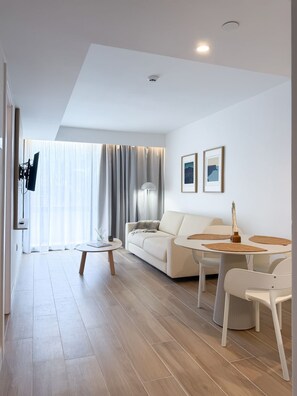 A modern living room with a sofa, a coffee table, and a dining area with chairs.