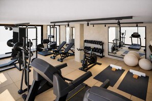 Uma academia com diversos equipamentos de exercícios, incluindo aparelhos de musculação, pesos livres e esteiras.